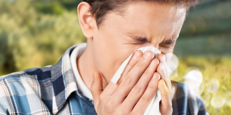 A young man sneezes and blows his nose