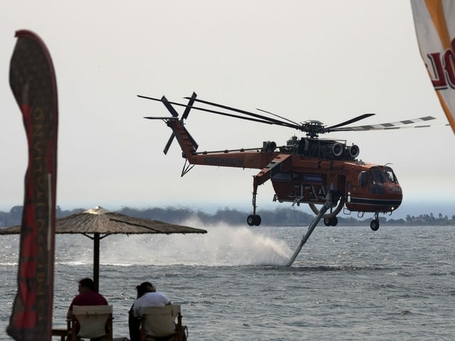 A helicopter resupplying water near the shore.