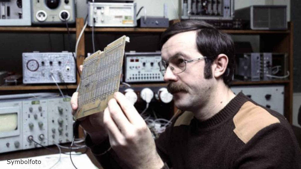 An engineer looks at an electronic component.