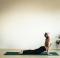 Woman yoga master doing poses on a mat in the home gym, dog pose (Urdhva Mukha Svanasana).