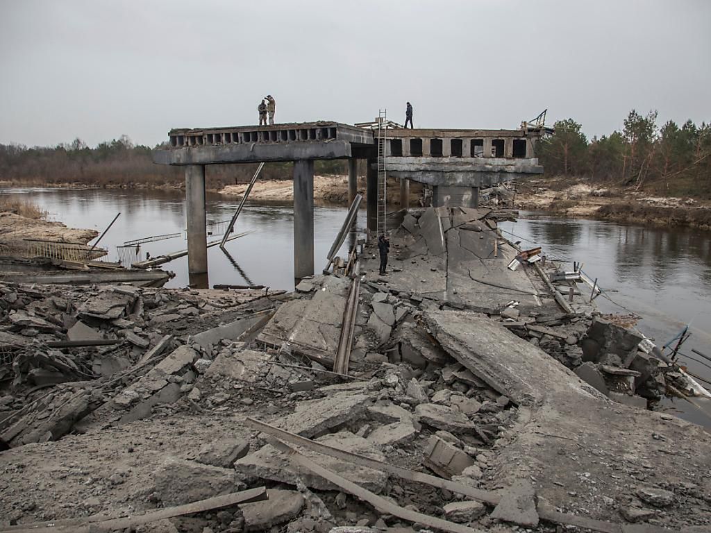 Ukrainian soldiers stand on a destroyed bridge between the village of Dytyatki and Chernobyl.