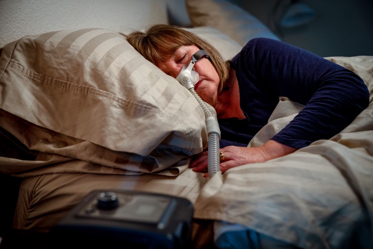 Middle-aged woman sleeping with a nose mask for people with obstructive sleep apnea.