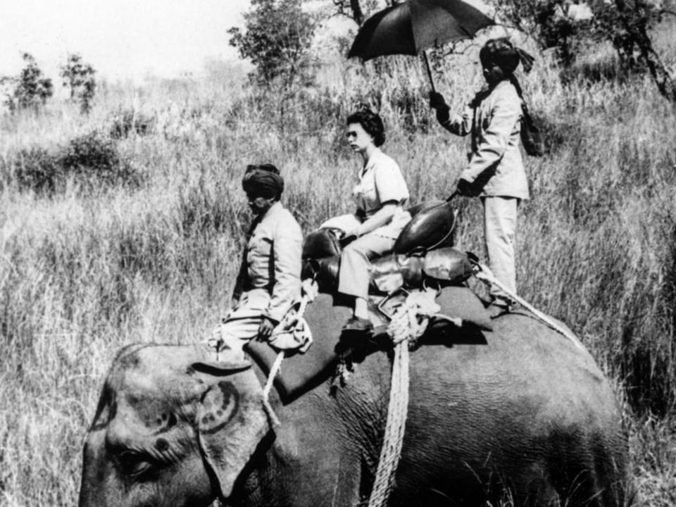 Black and white photo: a woman with two men in uniform on an elephant.