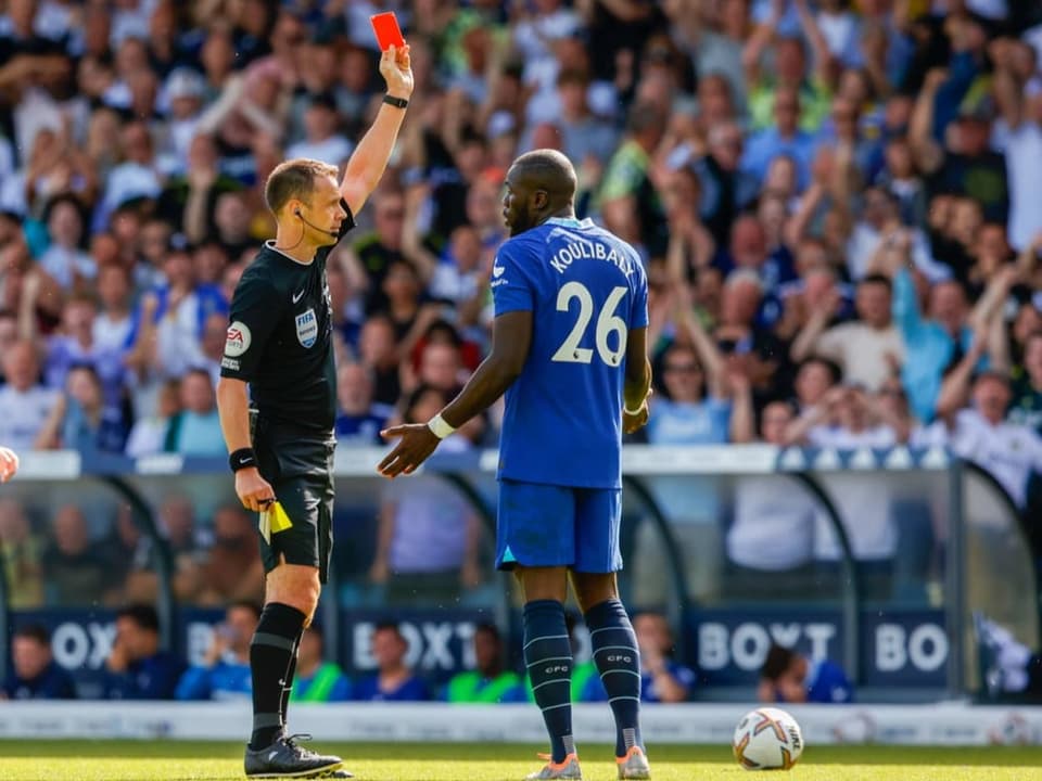 The referee shows the footballer the red card