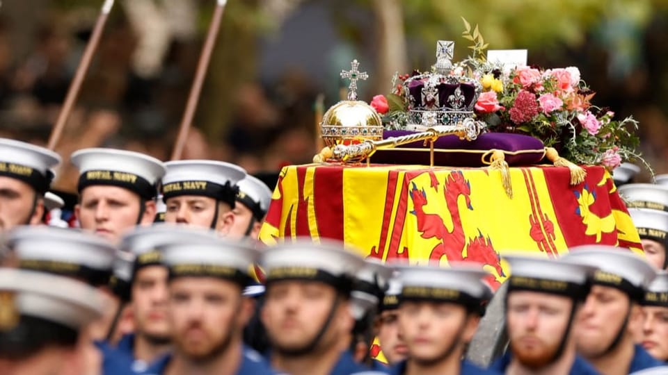 Soldiers pull the queen's coffin with a crown and a letter on it.